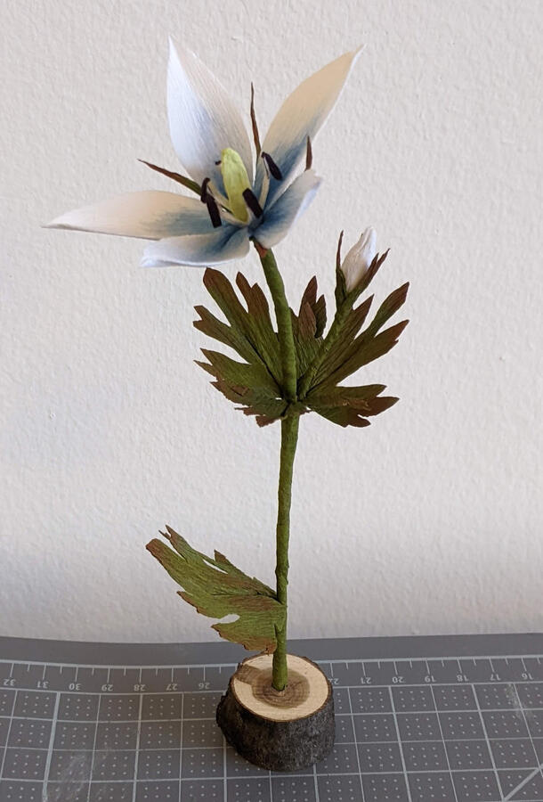 A crepe paper flower and small wood stand.